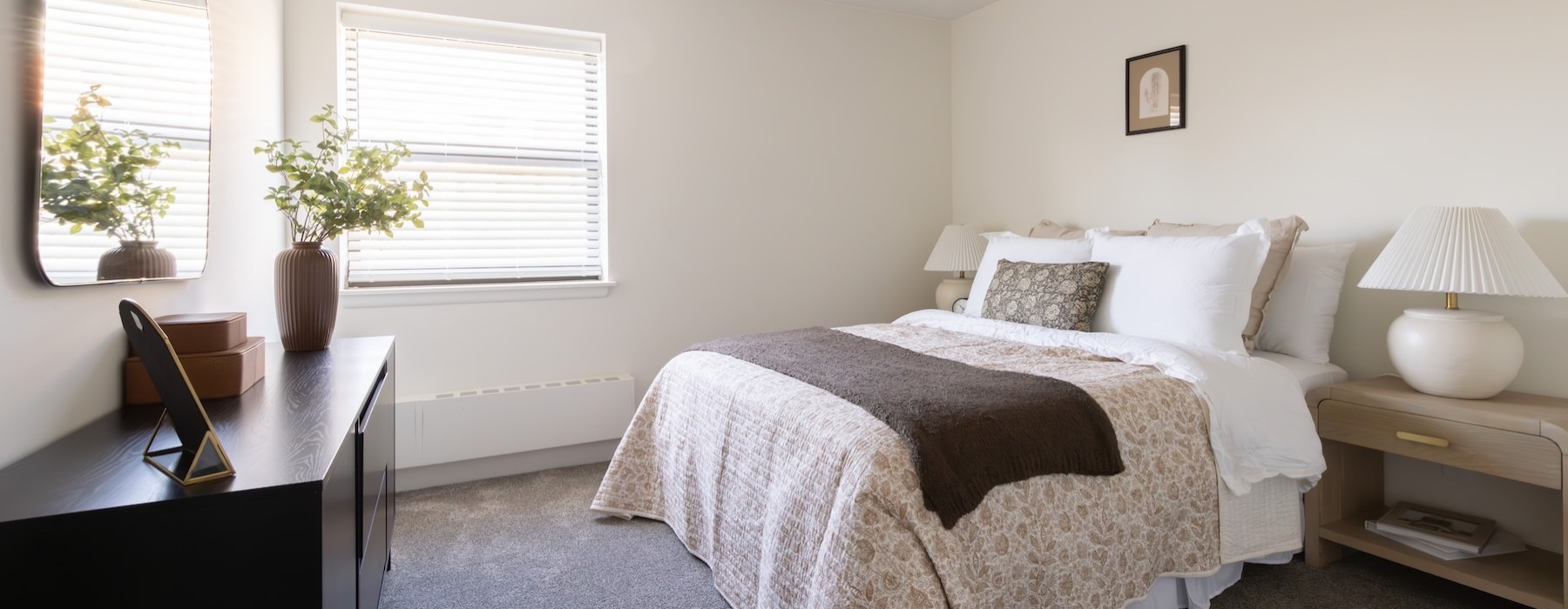 a bedroom with a bed, two nightstands, a dresser and a mirror